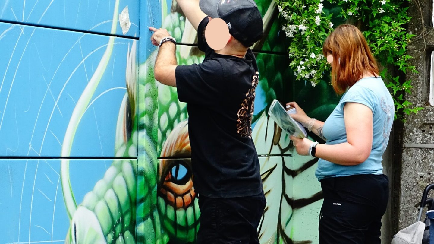 Artistes dessinant dragon et mandala calligraphique sur mur street art graffiti