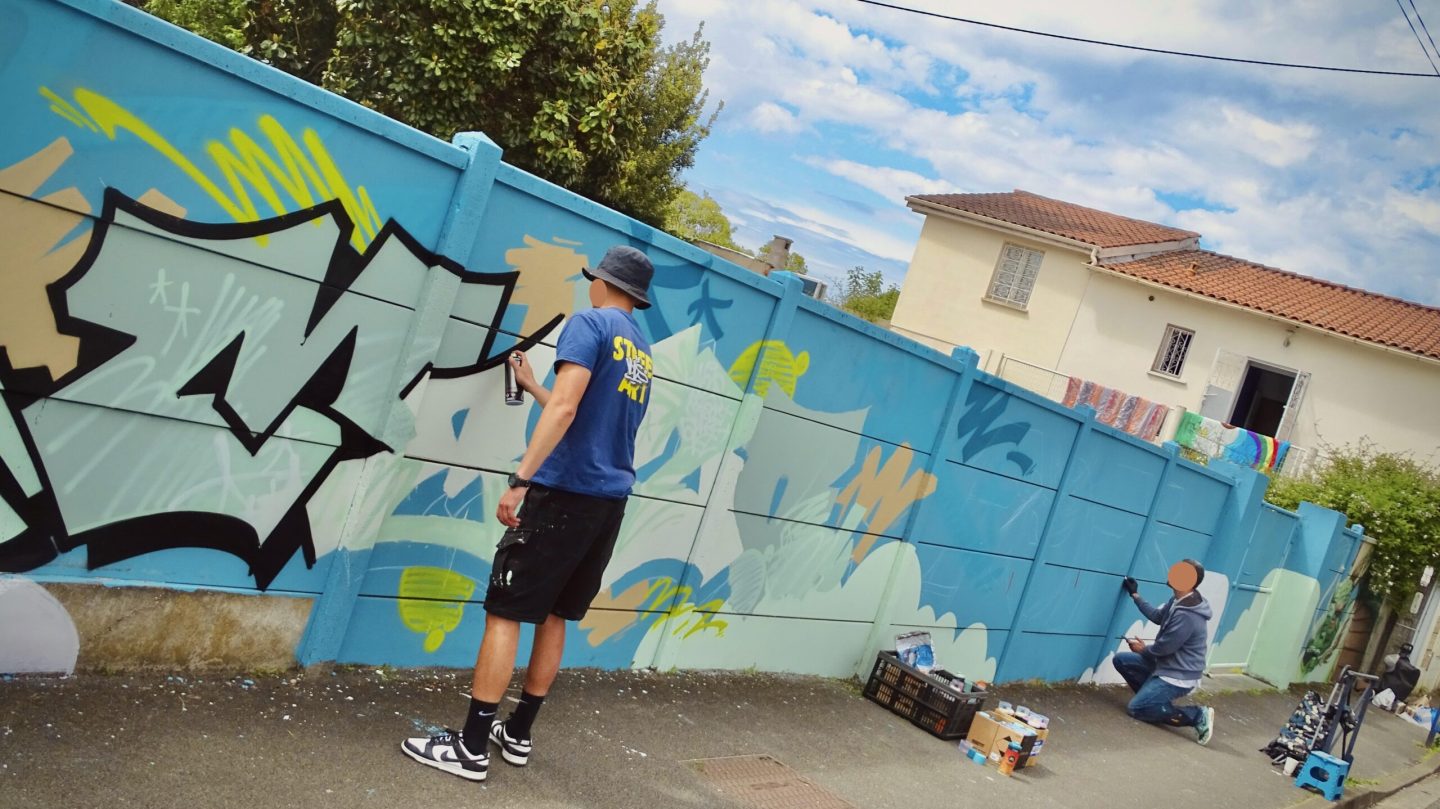 Artistes MEL20 et Pops traçant contours et esquisse de lettrage graffiti à Cenon