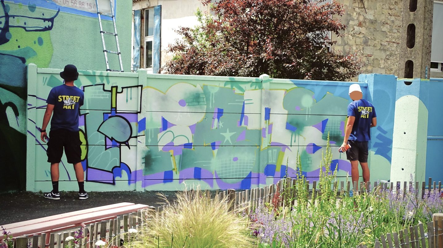 Artistes réalisant lettrage graffiti sur mur école Jeanne d’Arc Cenon