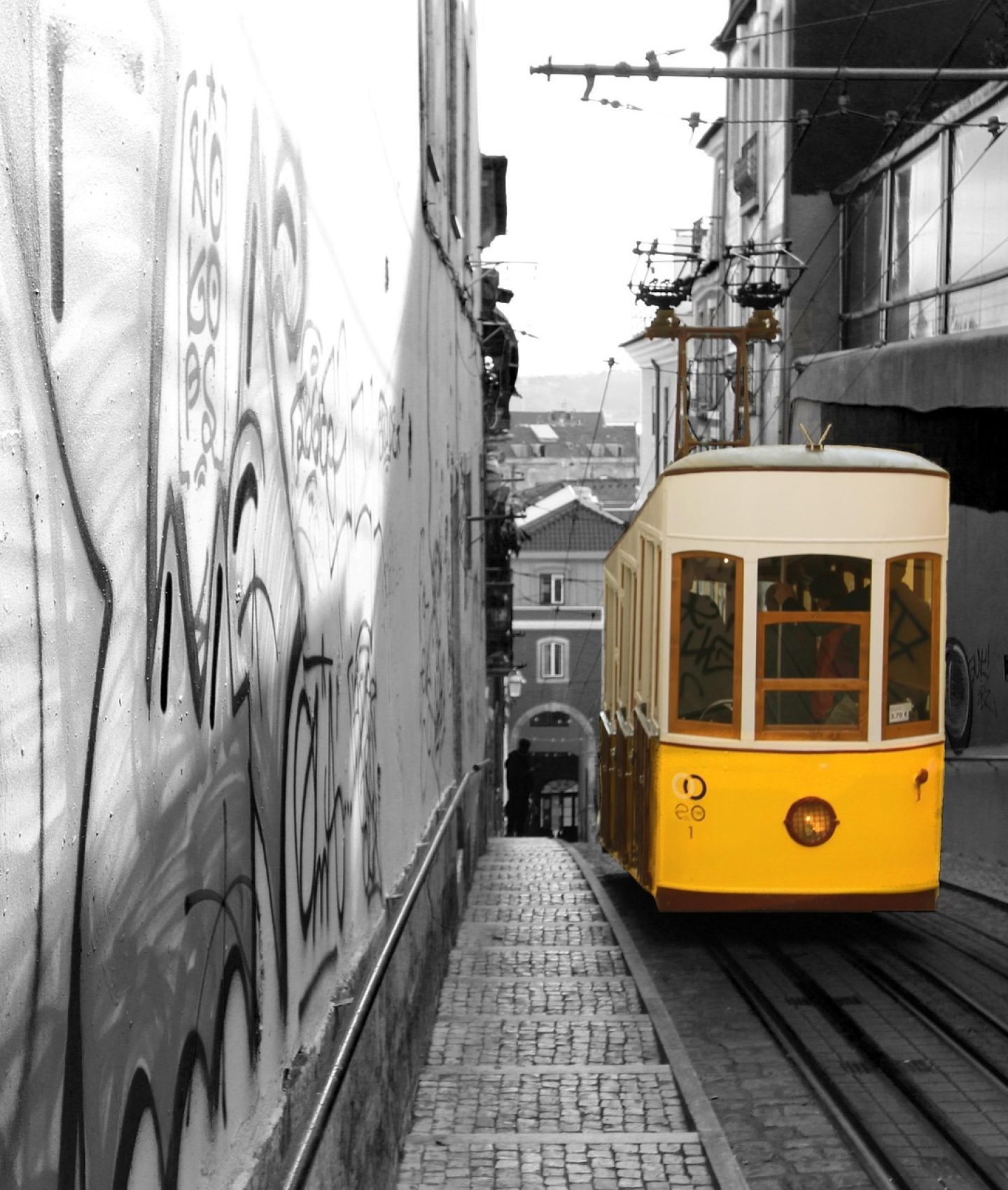 Funiculaire jaune circulant dans une rue urbaine couverte de graffitis et de street art au Portugal.