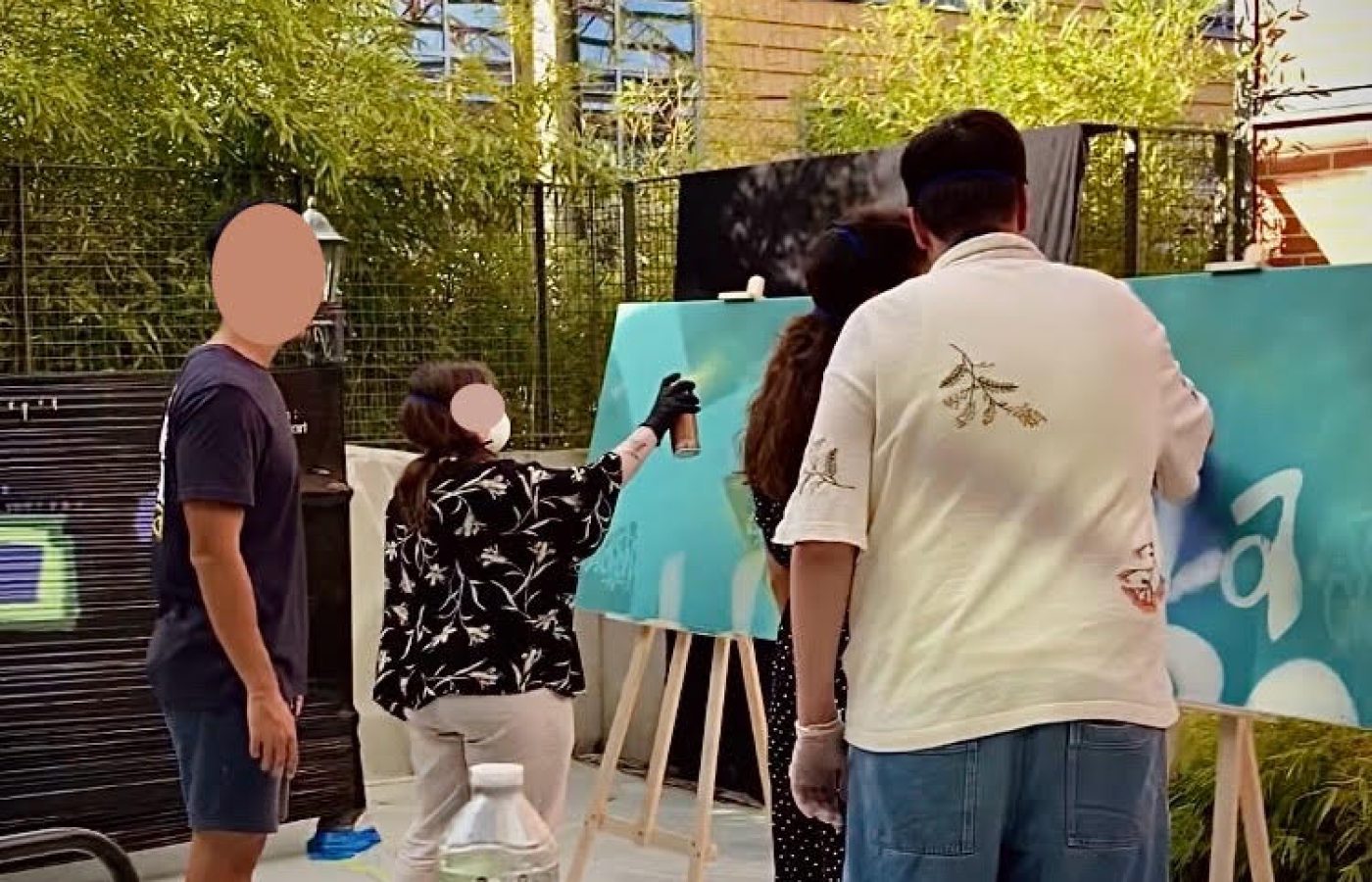 Employés d’Ubisoft Bordeaux peignant à la bombe sur des toiles lors d’un atelier graffiti collaboratif animé par WOLS Street Art.