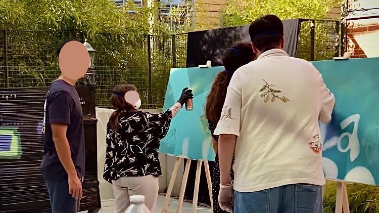 Employés d’Ubisoft Bordeaux peignant à la bombe sur des toiles lors d’un atelier graffiti collaboratif animé par WOLS Street Art.