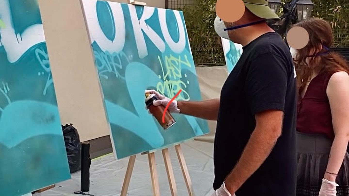Participant réalisant un tag à la bombe sur une toile pendant l’atelier street art WOLS Street Art chez Ubisoft Bordeaux.