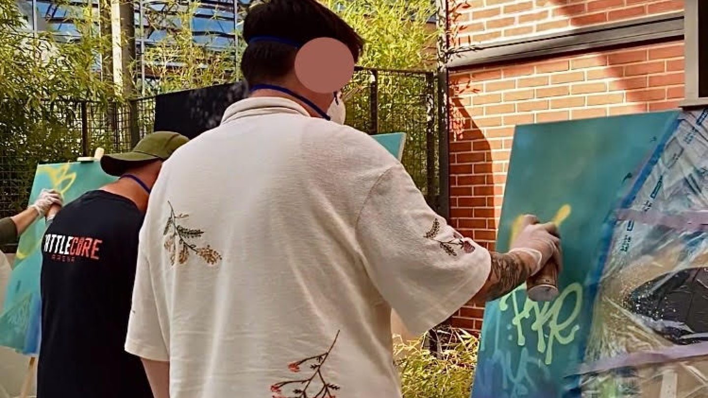 Employés d’Ubisoft Bordeaux personnalisant des toiles à la bombe lors d’un atelier graffiti collectif avec WOLS Street Art.