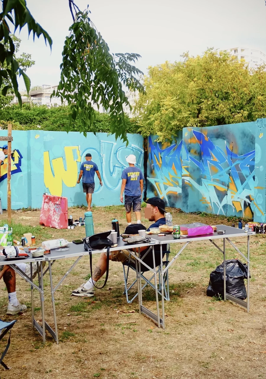 Graffeurs réalisant plusieurs fresques sur un mur lors du WOLS Open Spray #2