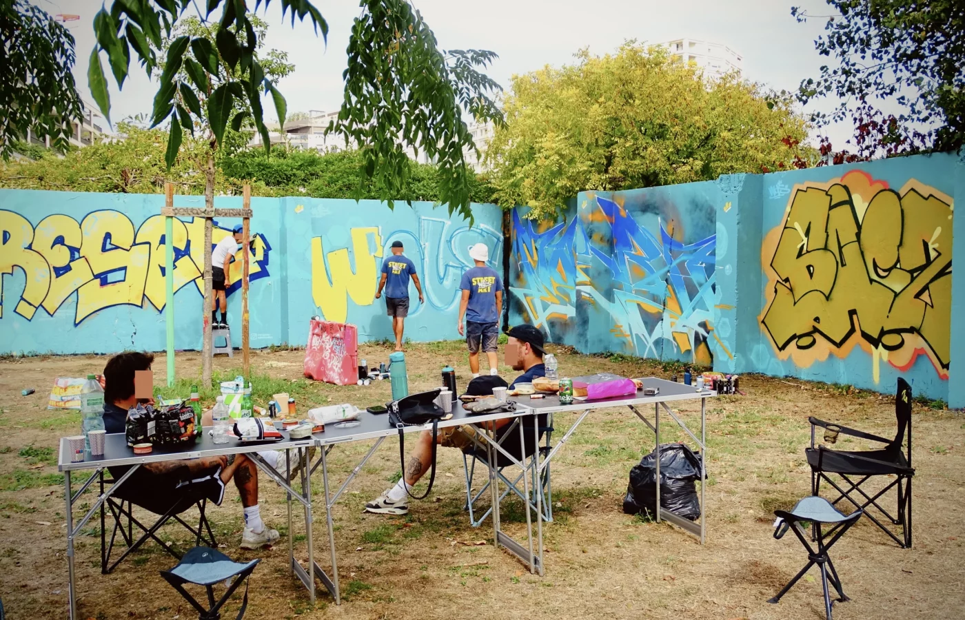 Graffeurs réalisant plusieurs fresques sur un mur lors du WOLS Open Spray #2