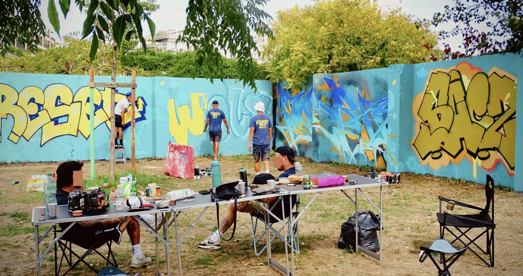Graffeurs réalisant plusieurs fresques sur un mur lors du WOLS Open Spray #2